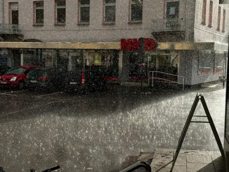Hevige regenbui op een straat met geparkeerde auto's - het soort bui waarbij een verstopte dakgoot in Rotterdam overloopt